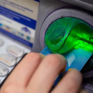 Eine Bankkundin steckt ihre Girokarte in einen Geldautomaten.