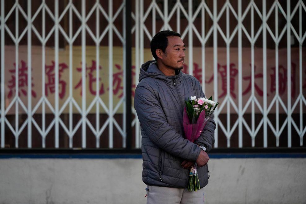 Hunter Zhao, 41, hält Blumen zu Ehren der Opfer, die bei Schüssen in einem Tanzstudio in Monterey Park, Kalifornien, getötet wurden.