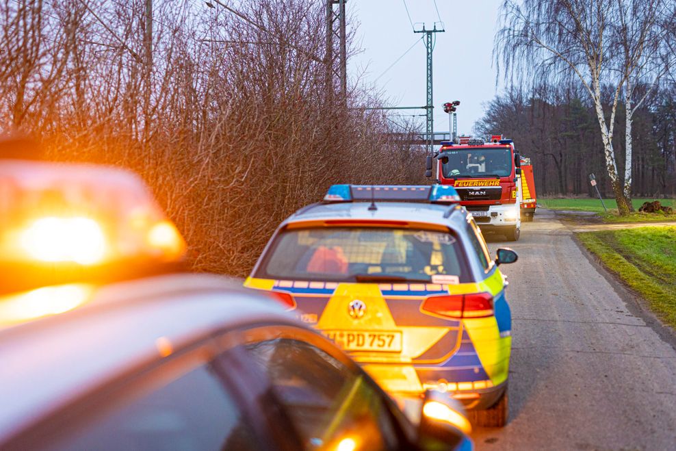 Einsatzfahrzeuge von Polizei und Feuerwehr stehen an einem Waldstück in der Region Hannover.