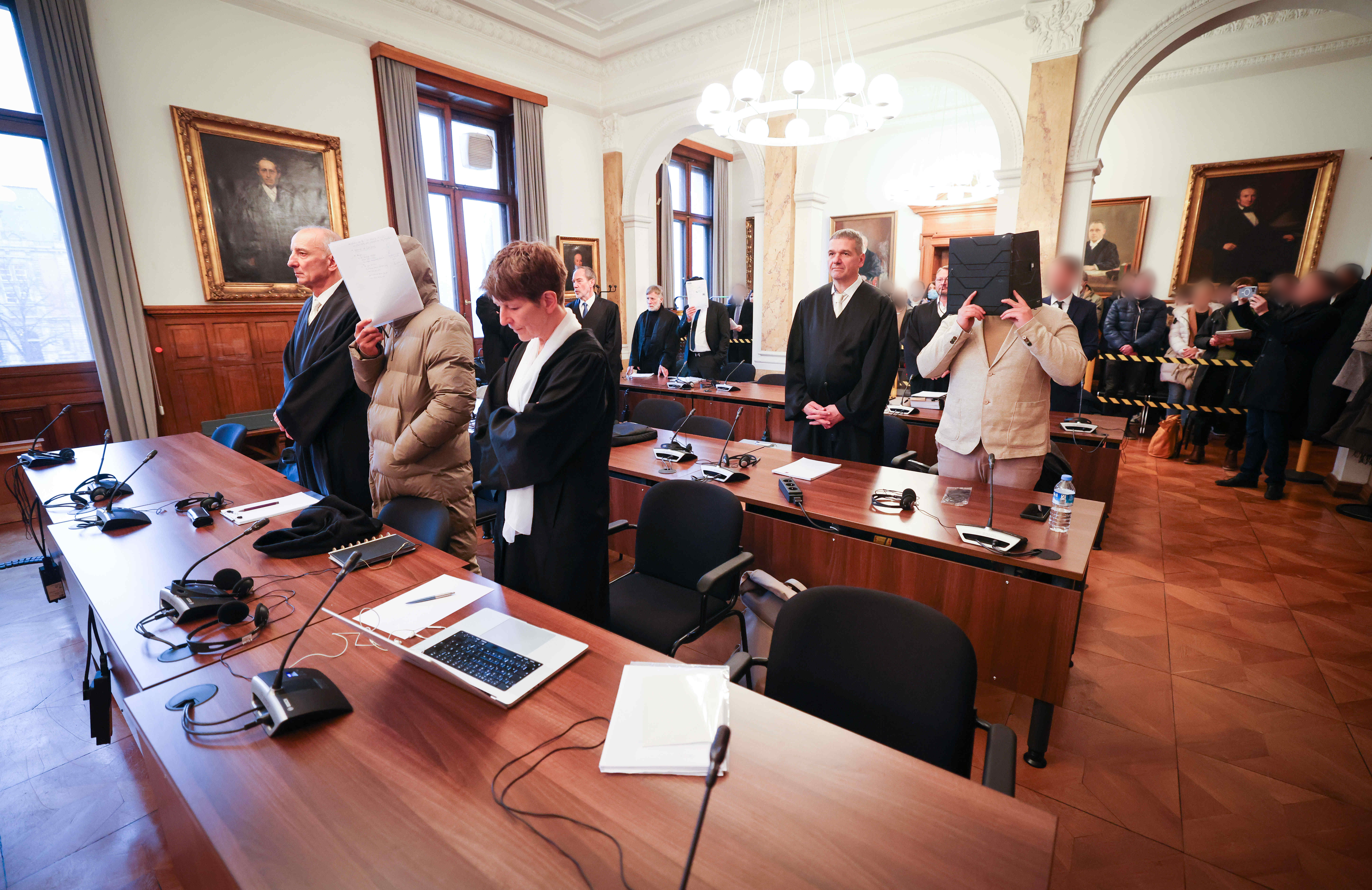 Die Angeklagten und ihre Anwälte stehen im Gerichtssaal im Ziviljustizgebäude in Hamburg.