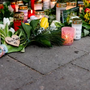 Blumen, Kerzen und verschiedene Bilder sind im Wartehäuschen am Bahnhof zum Gedenken an die Opfer der Messerattacke niedergelegt.