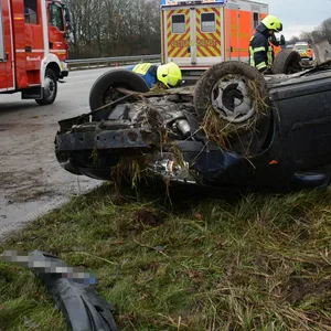Ein Auto liegt auf dem Dach, daneben Feuerwehrleute