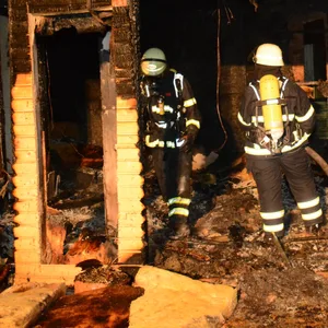 Feuerwehrkräfte bei einem Kontrollgang durch die zerstörte Laube.