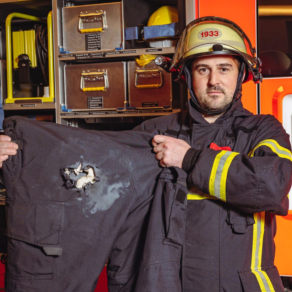 Ein Feuerwehrmann zeigt seine Einsatzhose, die von einem Böller zerfetzt wurde.