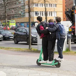 Drei Kinder auf einem E-Scooter