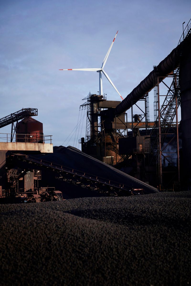 Ein Windrad im Hintergrund des ArcelorMittal-Geländes in Hamburg. Windenergie spielt für die Produktion schon heute eine entscheidende Rolle.