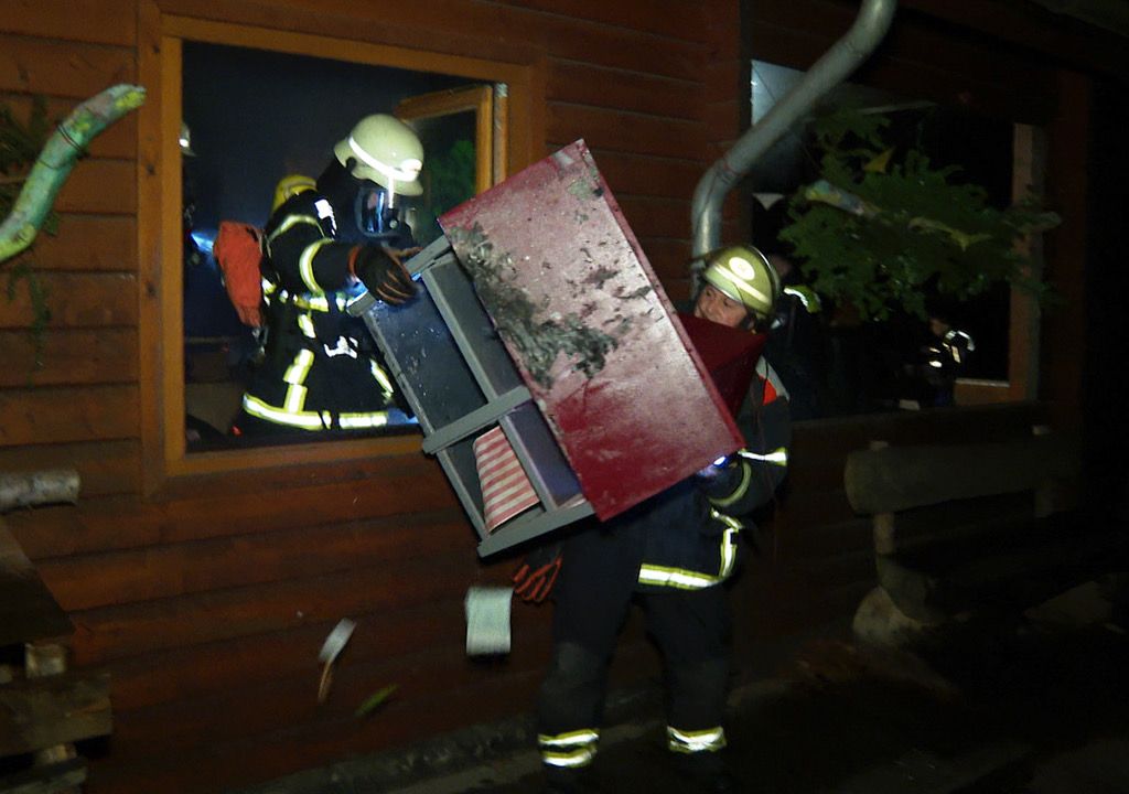 Feuerwehrkräfte bringen eine Art Puppenhaus aus der Kita. Diverse Möbel und Gegenstände waren in Brand geraten.