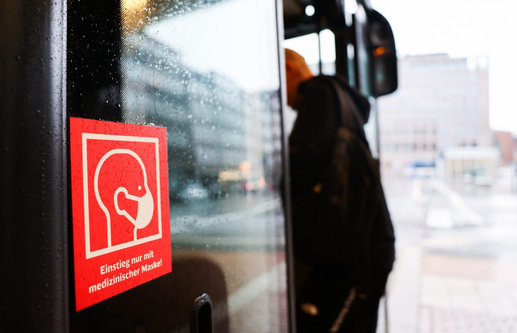 Ein Aufkleber an der Tür eines Linienbusses verweist auf das tragen einer medizinischen Maske.