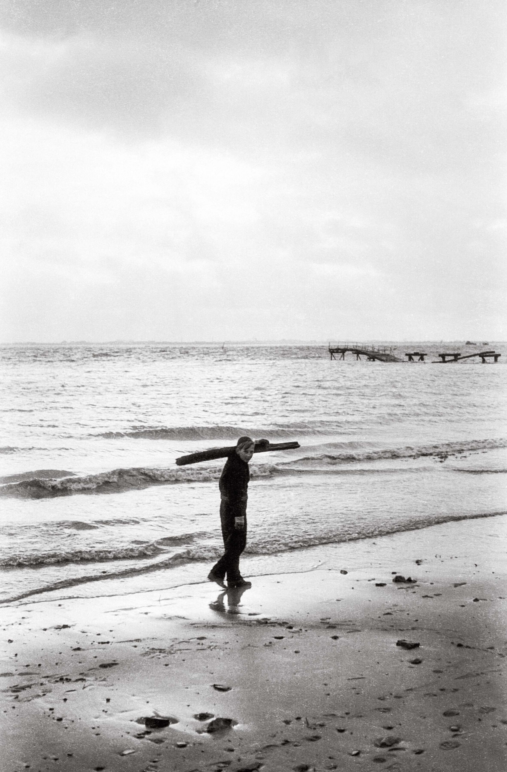 Foto von 1949. Ein Junge sammelt Holz am Strand.