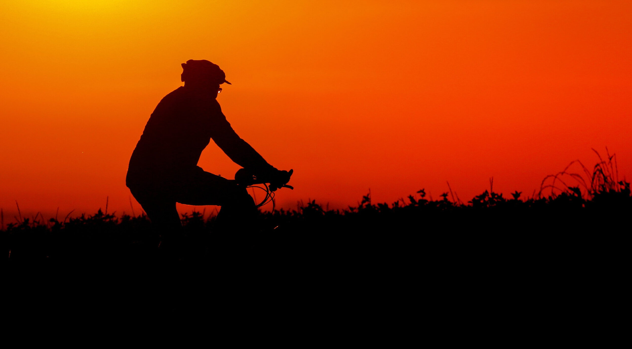 Ein Radfahrer ist am Morgen kurz vor Sonnenaufgang mit seinem Fahrrad unterwegs.