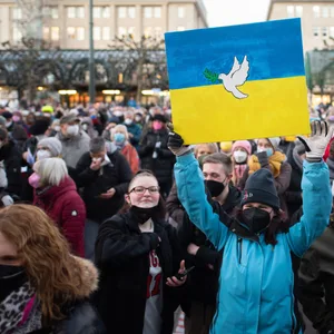 Zahlreiche Menschen singen bei einer Demonstration unter dem Motto «Singen für den Frieden» auf dem Rathausmarkt, dabei halten sie Plakate mit einer Friedenstaube in den Farben der Ukraine.