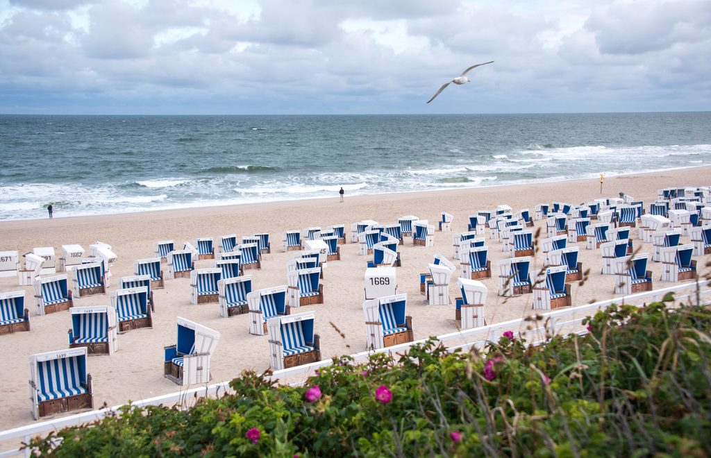 Zwei Spaziergänger sind am Morgen am Strand von Westerland an der Nordsee unterwegs.