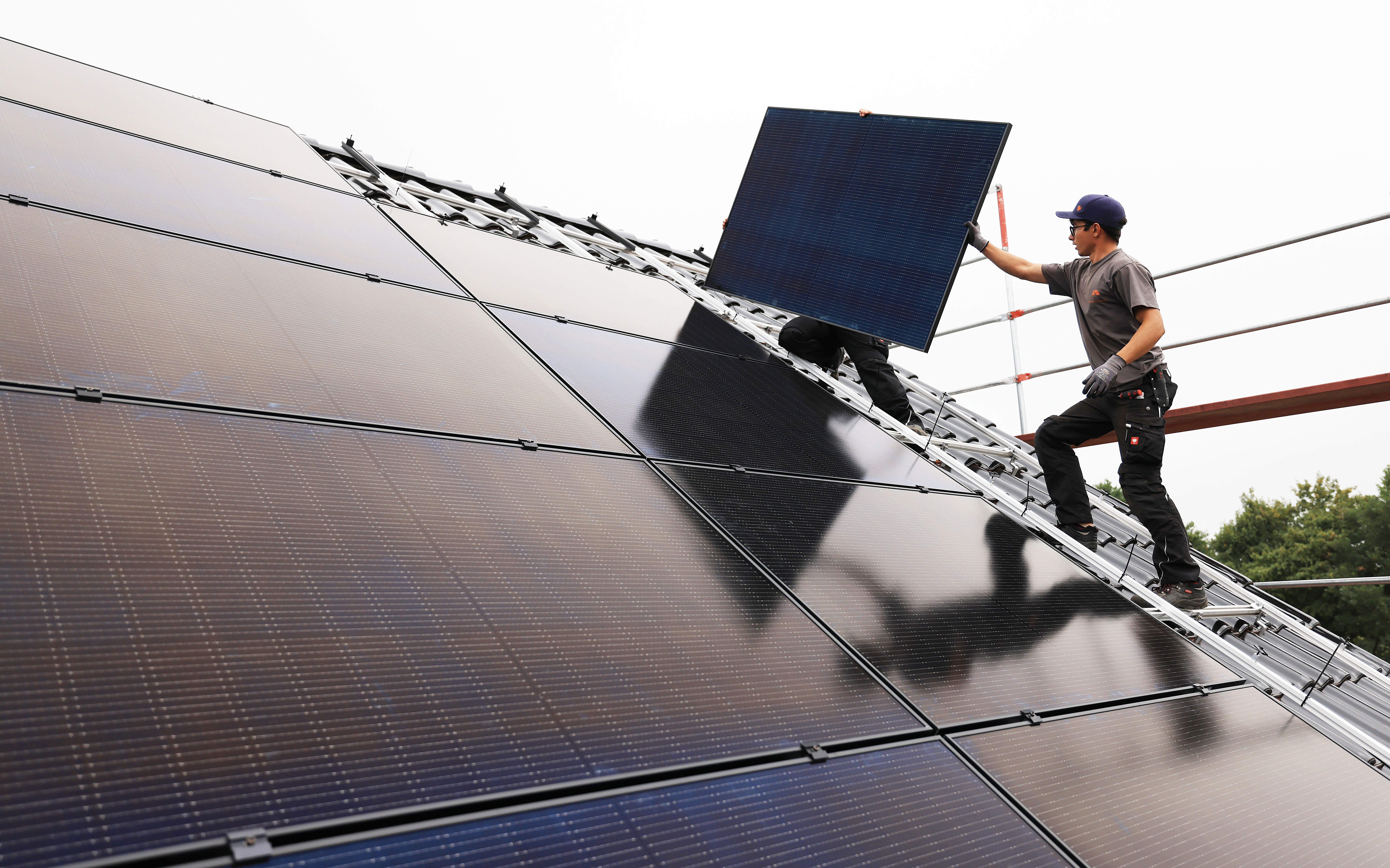 Handwerker montieren auf dem Dach eines Wohnhauses Solarmodule. (Symbolbild)