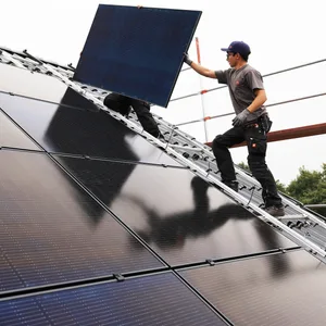 Handwerker montieren auf dem Dach eines Wohnhauses Solarmodule. (Symbolbild)