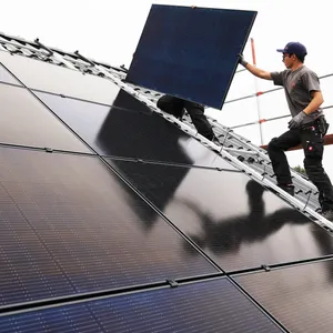 Handwerker montieren auf dem Dach eines Wohnhauses Solarmodule. (Symbolbild)