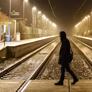 Ein Mann geht im Morgengrauen über den Bahnübergang des Bahnhof von Brokstedt
