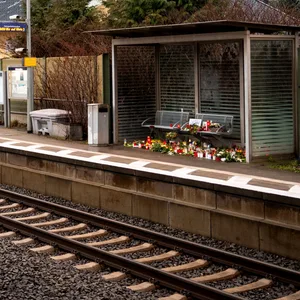 Kerzen und Blumen stehen und liegen im Bahnhof Brokstedt in einem Wartehäuschen.