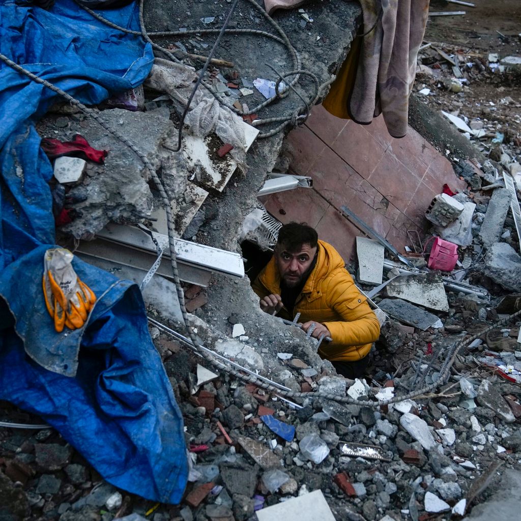 Ein Mann sucht nach Menschen in den Trümmern eines zerstörten Gebäudes.
