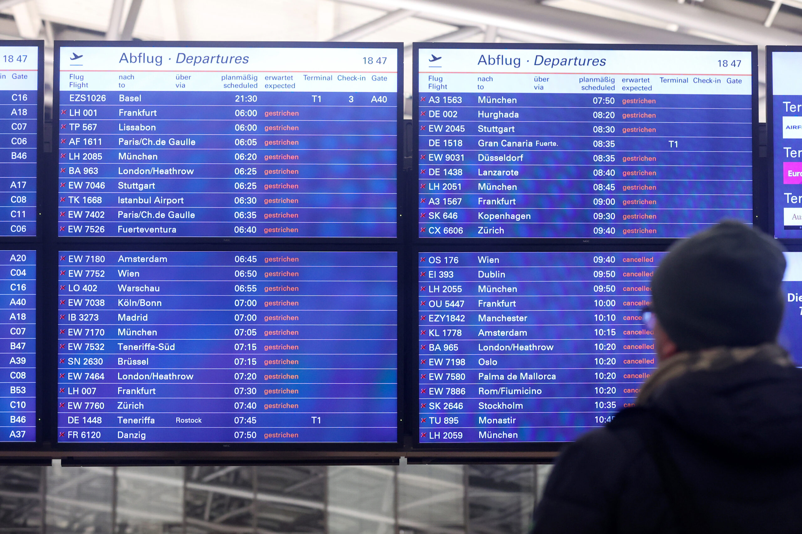 Ein Mann schaut am Flughafen Hamburg auf eine Anzeigentafel, auf der zahlreiche gestrichene Flüge angezeigt werden