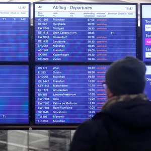 Ein Mann schaut am Flughafen Hamburg auf eine Anzeigentafel, auf der zahlreiche gestrichene Flüge angezeigt werden