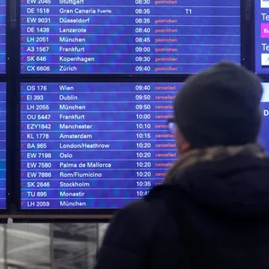 Ein Mann schaut am Flughafen Hamburg auf eine Anzeigentafel, auf der zahlreiche gestrichene Flüge angezeigt werden.