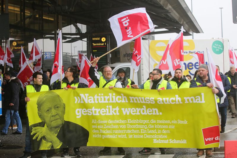 Streikende Mitarbeiter stehen während einer Demonstration und Zwischen-Kundgebung vor dem Terminal 1 am Flughafen Hamburg.