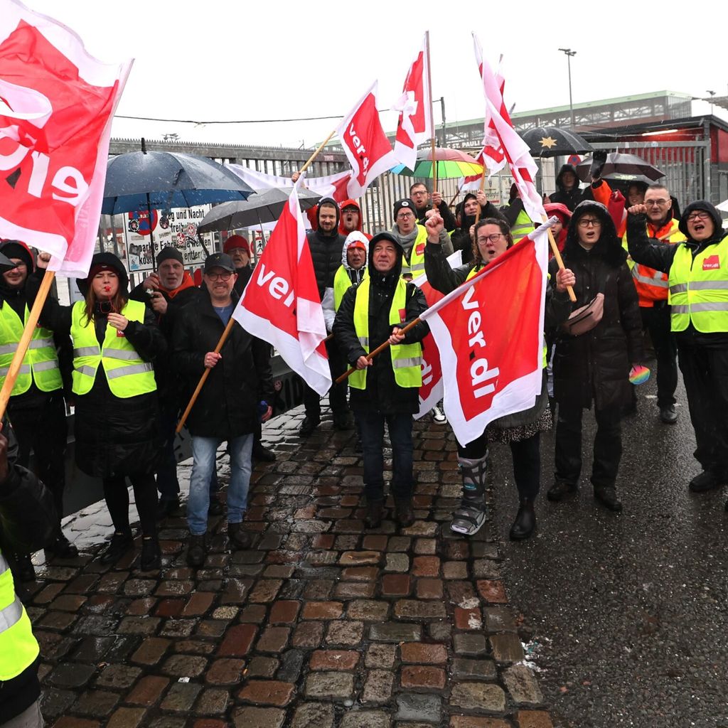 Beschäftigte von Recyclinghöfen und Verdi-Mitglieder stehen nach einer Abschlusskundgebung zu ihrem Warnstreik vor den geschlossenen Toren des Recyclinghofs St. Pauli.