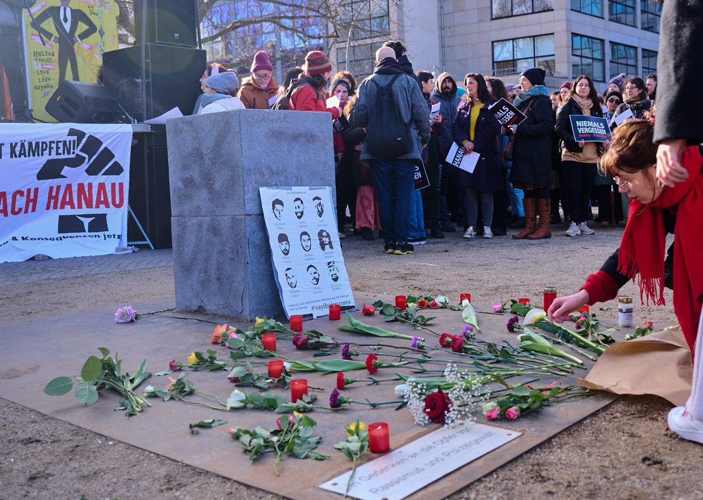 Bei der Gedenkveranstaltung eines Bündnisses von Initiativen und Organisationen auf dem Oranienplatz legt eine Frau eine Blume nieder.