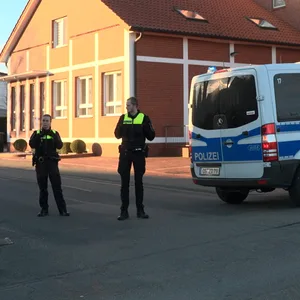 Polizisten sperren die Straße ab. Zwei Menschen sind in der Nähe einer Grundschule in Bramsche (Landkreis Osnabrück) durch Schüsse schwer verletzt worden.