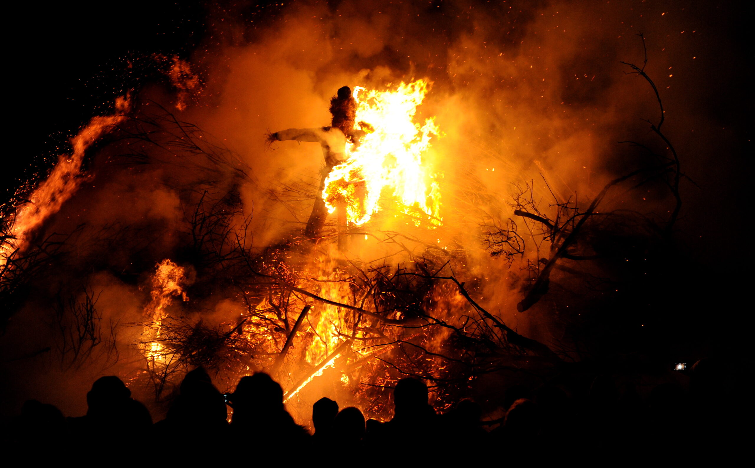 Besucher stehen vor einer brennenden Strohpuppe im traditionellen Biikefeuer in Simonsberg bei Husum (Schleswig-Holstein)
