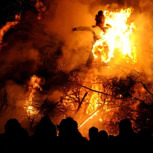 Besucher stehen vor einer brennenden Strohpuppe im traditionellen Biikefeuer in Simonsberg bei Husum (Schleswig-Holstein)