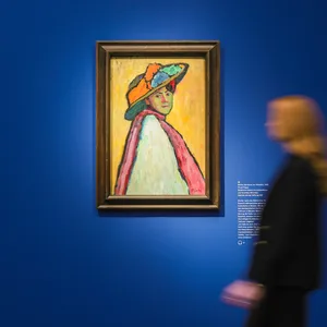 Einblick in die Ausstellung. An einer sehr blauen Wand hängt Gabriele Münters Porträt „Bildnis Marianne von Werefkin“ aus dem Jahr 1909
