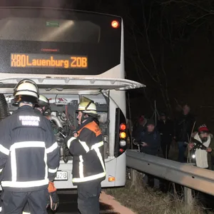 Während die Feuerwehr den Brand löscht, stehen die Passagiere hinter der Leitplanke.