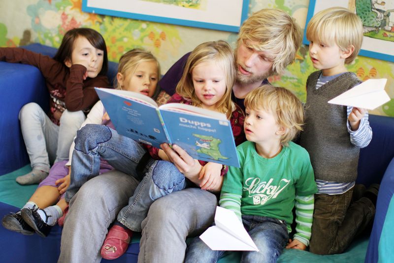 Ein Erzieher liest mit Kindern in der Kita.