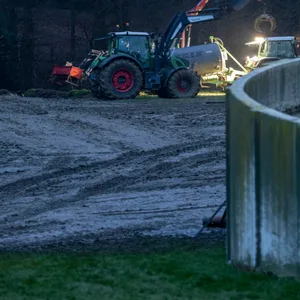 Ein Landwirt mit Helfern versucht die Gülle von seinem Feld zu beseitigen.