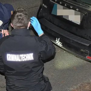 Ermittler der Kriminaltechnik untersuchen ein Einschussloch am Auto in Eimsbüttel