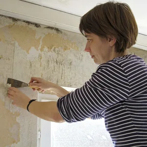 Frau entfernt Schimmel an der Wand