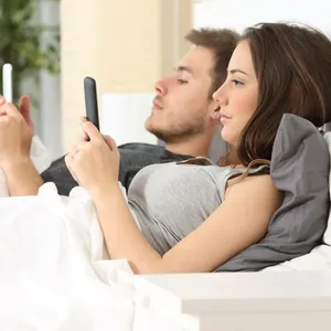 Paar mit Handy im Bett