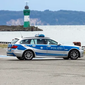 Zwei Polizeiautos stehen auf der Pier im Faehrhafen Mukran