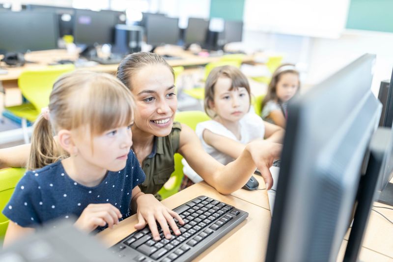 Eine Lehrerin unterrichtet Schülerinnen im Computer-Unterricht.