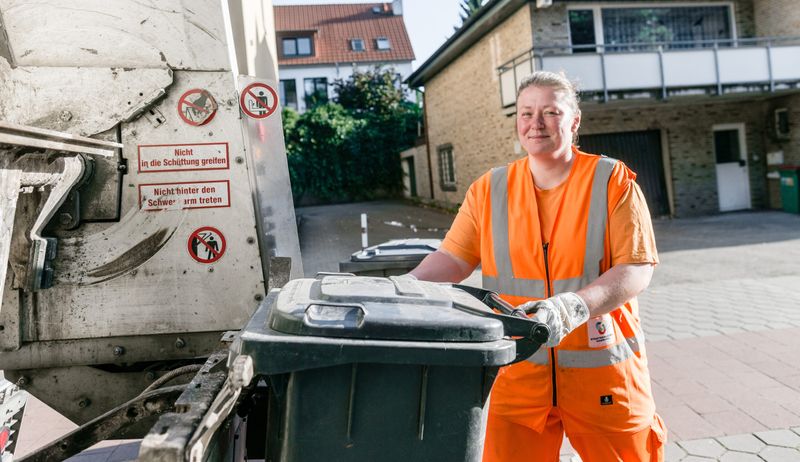 Eine Entsorgerin der Stadtreinigung im Einsatz an der Tonne.