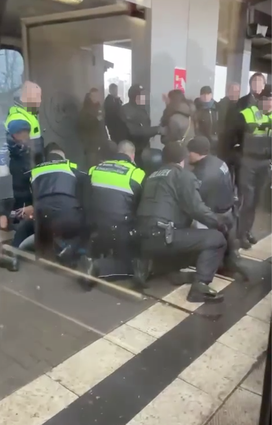 Mitarbeiter der S-Bahn-Wache und Polizisten fixieren den Mann am Boden.