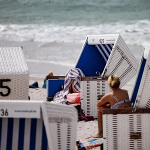 Besucher des Strands genießen die Sonne in Strandkörben.