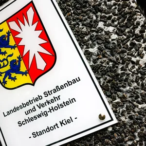 Ein Hinweisschild auf den Sitz vom Landesbetrieb Straßenbau und Verkehr hängt am Eingang zur Hauptstelle.