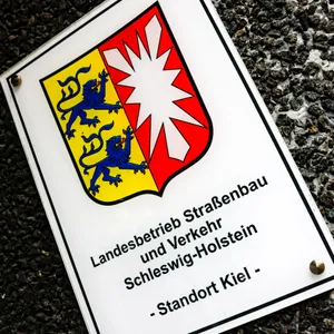 Ein Hinweisschild auf den Sitz vom Landesbetrieb Straßenbau und Verkehr hängt am Eingang zur Hauptstelle.