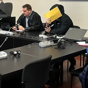 Der Angeklagte verbirgt sein Gesicht vor der Kamera.