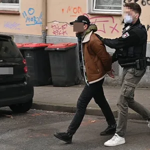 Polizisten führen einen Verdächtigen ab.