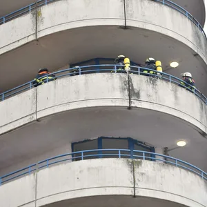 Feuerwehrkräfte in einem Laubengang des Hochhauses.