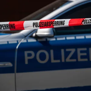 Ein Polizeiauto steht hinter einem Absperrband (Symbolfoto).