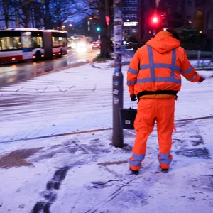 Ein Mitarbeiter der Stadtreinigung Hamburg streut nach leichtem Schneefall ein Salz-Sandgemisch an einer Fußgängerampel